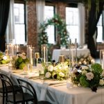 Elegant Columbus wedding reception with lush green and white floral centerpieces, candlelight and modern black chairs.