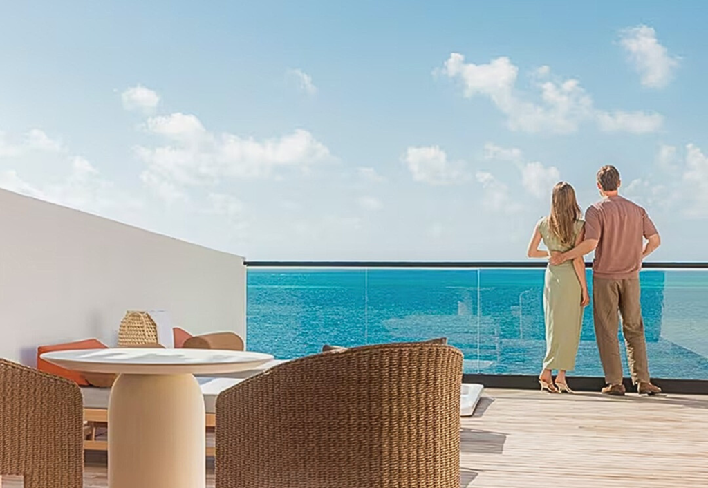 Newlyweds embracing on private terrace overlooking turquoise ocean waters at luxury resort