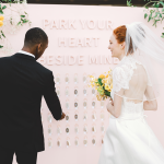 Bride and groom share first look moment before pink sign reading "Park Your Heart Beside Mine"