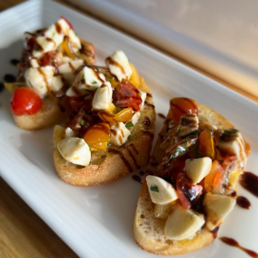 Gourmet bruschetta appetizers topped with tomatoes, mozzarella, and balsamic glaze on toasted crostini