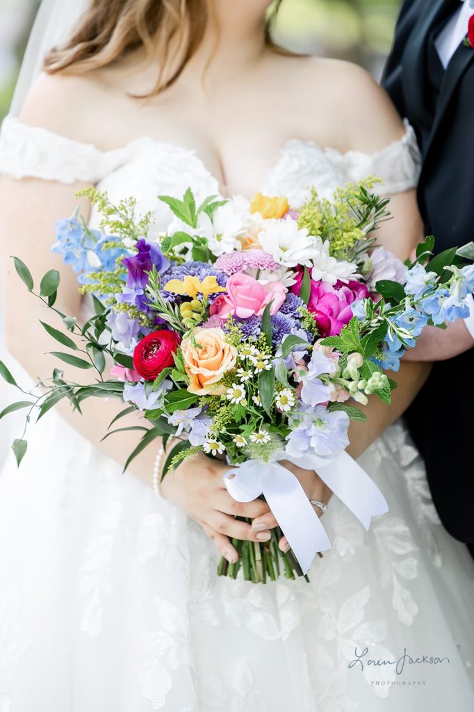 Colorful wildflower bridal bouquet with pink, blue, purple, yellow, and red blooms