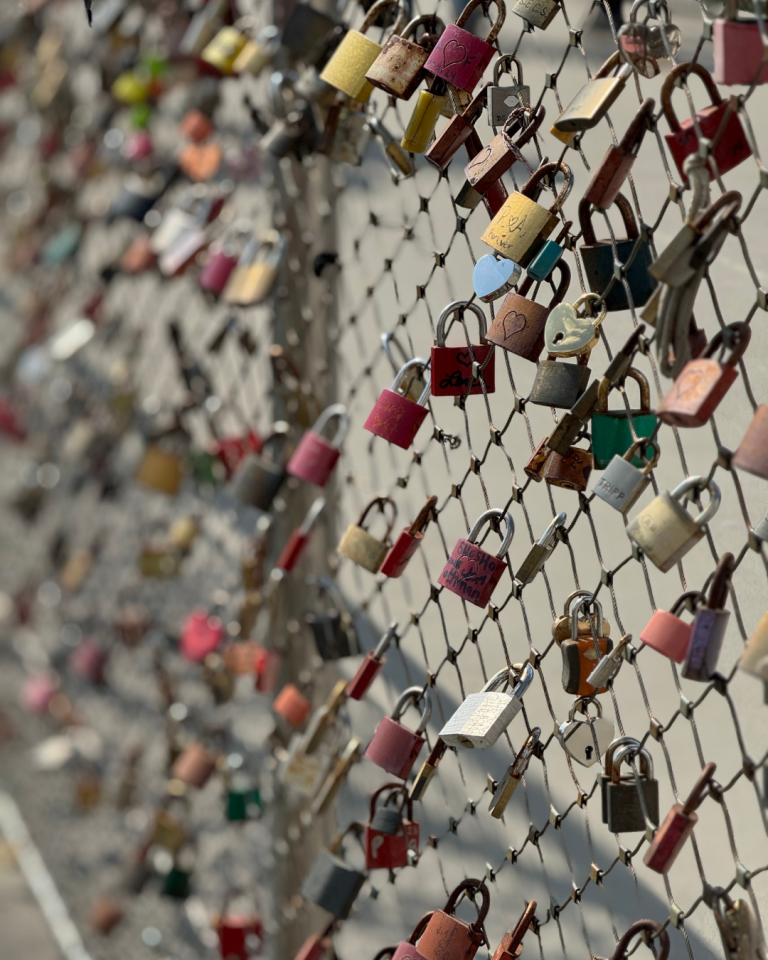 fence with different colored locks with hearts and initials on the locks