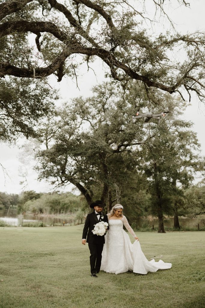 Bride and groom standing beneath sprawling oak tree on green lawn