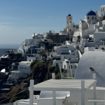 White-washed buildings and blue-domed churches cascade down cliffside in Santorini, Greece, a popular destination wedding location