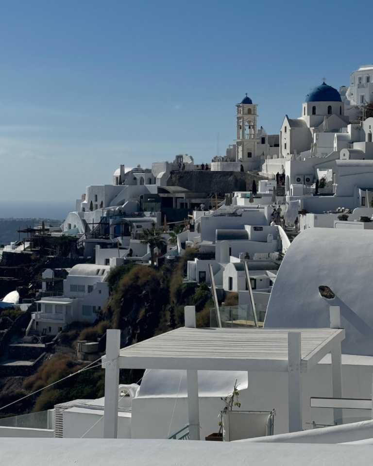 White-washed buildings and blue-domed churches cascade down cliffside in Santorini, Greece, a popular destination wedding location