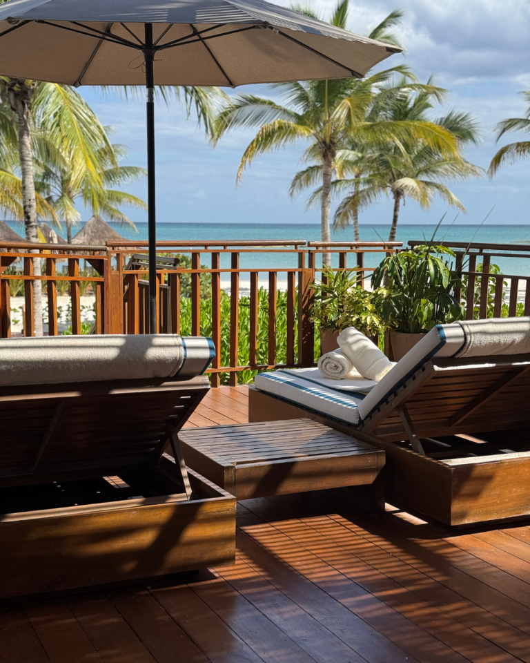 Private beachfront terrace with lounge chairs and palm trees overlooking turquoise ocean, ideal for destination wedding relaxation