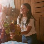 Smiling woman holding colorful bouquet at flower workshop table