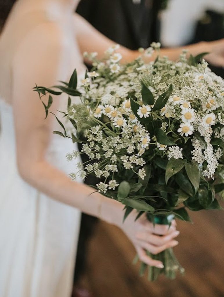 Bride holding lush bouquet of white flowers and greenery