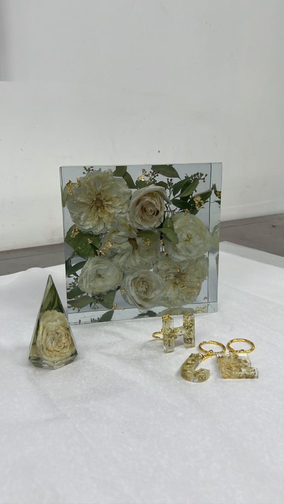 Preserved white wedding flowers and gold rings displayed in clear resin keepsake blocks and frame