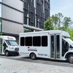 Riches & Roses branded white shuttle buses parked at modern building for wedding transportation service
