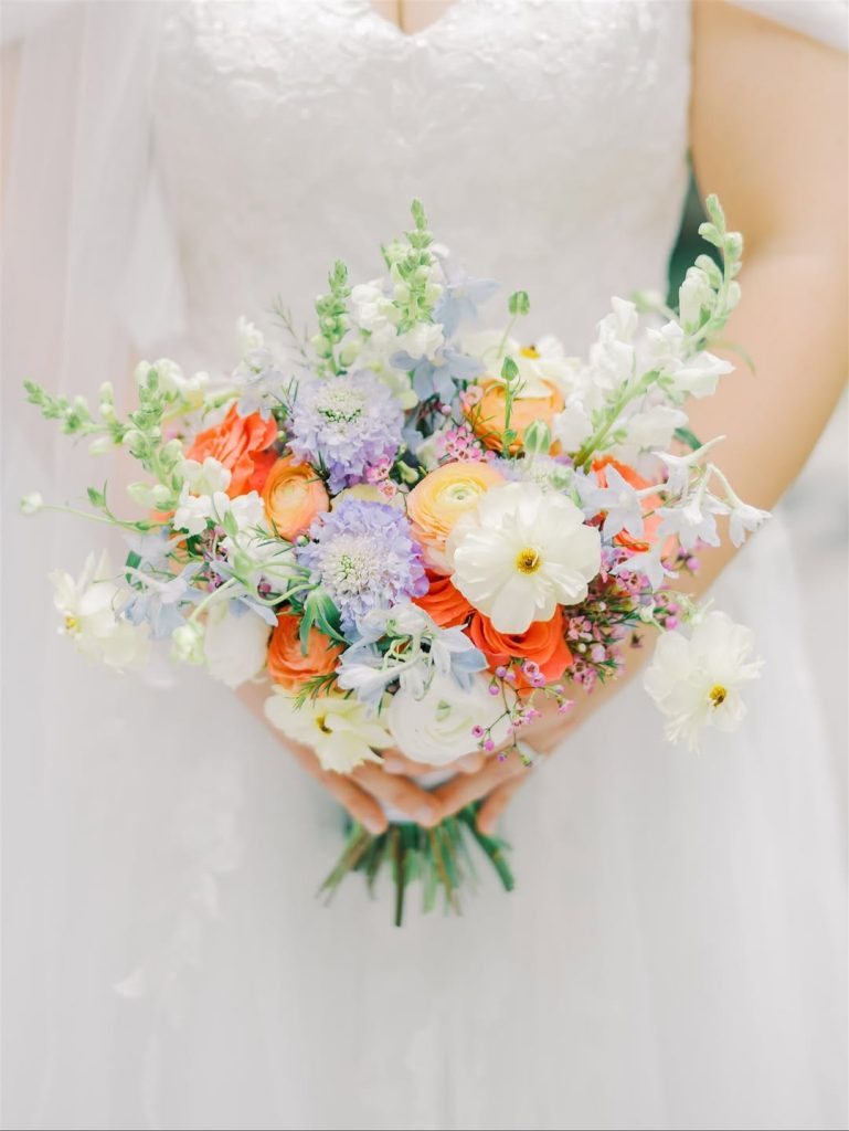 Bride holding vibrant bouquet with orange, purple, and white blooms