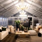 Greenhouse lounge space with vaulted ceiling, chandelier lighting, and modern white seating