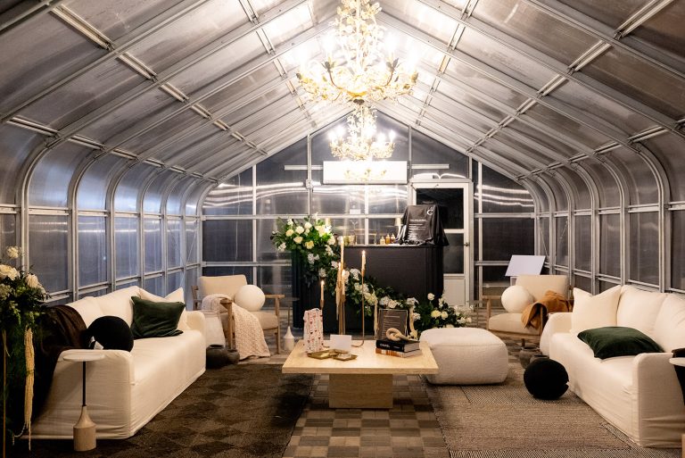 Greenhouse lounge space with vaulted ceiling, chandelier lighting, and modern white seating