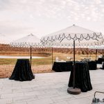 Outdoor cocktail area with black-draped tables and string lights at vineyard