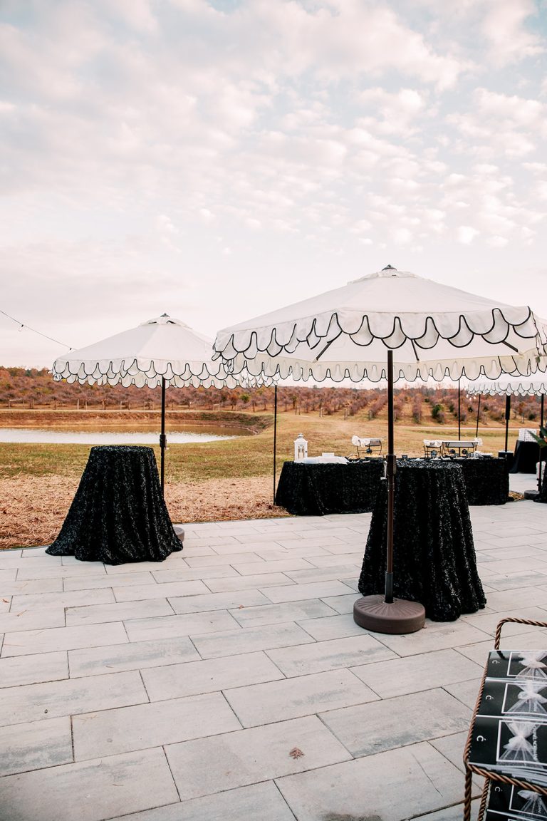 Outdoor cocktail area with black-draped tables and string lights at vineyard