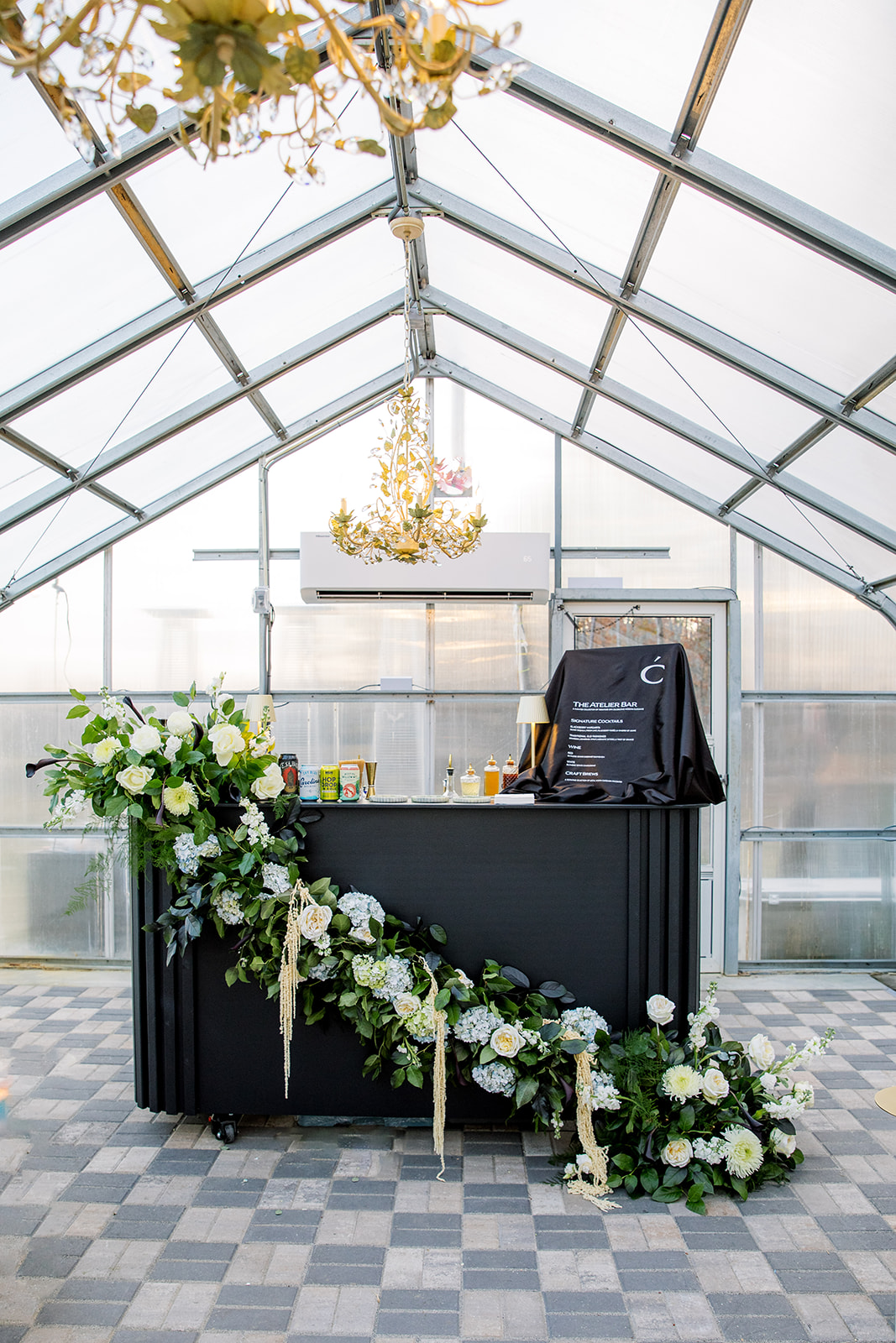 Black bar with cascading white and blue florals inside greenhouse wedding venue