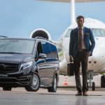 black transportation van and airplane in the background of man walking away with briefcase