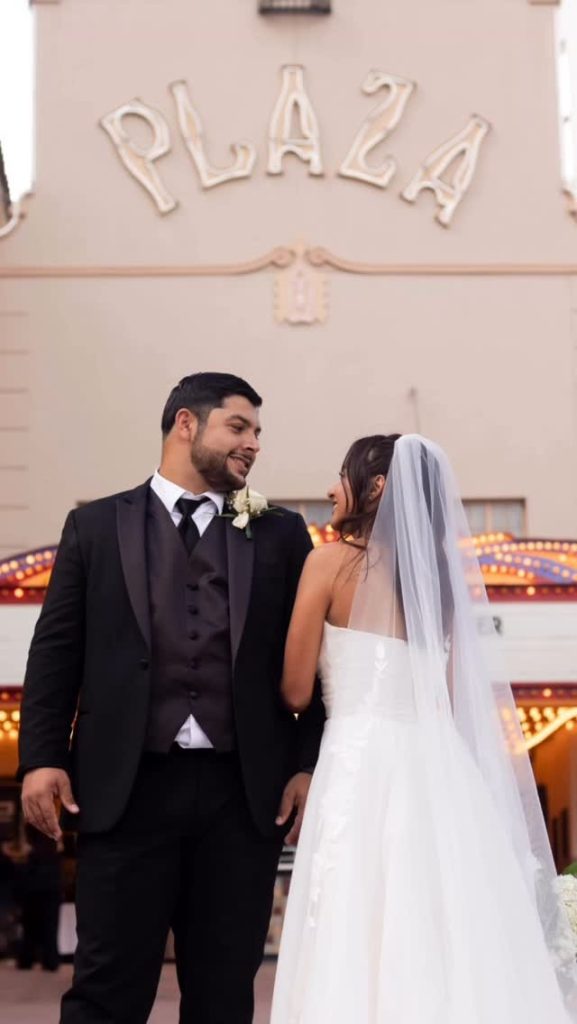Bride and groom holding hands outside historic Plaza Theatre with vintage marquee lights in El Paso