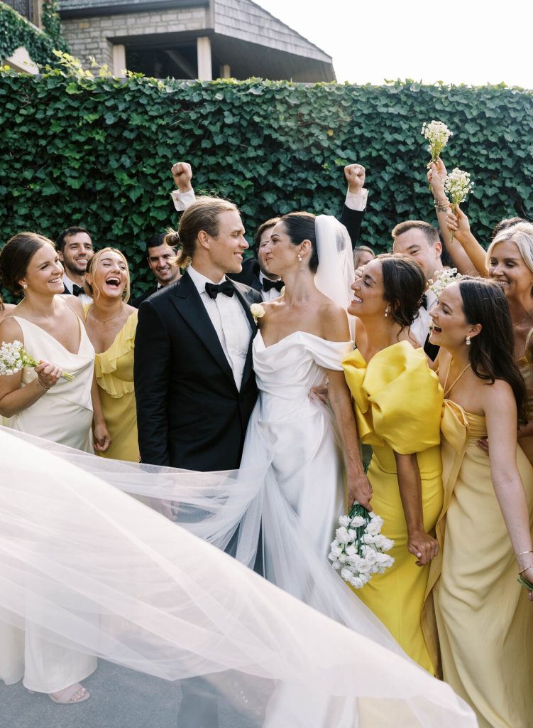 Newlyweds celebrating with wedding party in yellow dresses holding bouquets