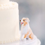 white two tiered cake with white and brown dog figurine on the side