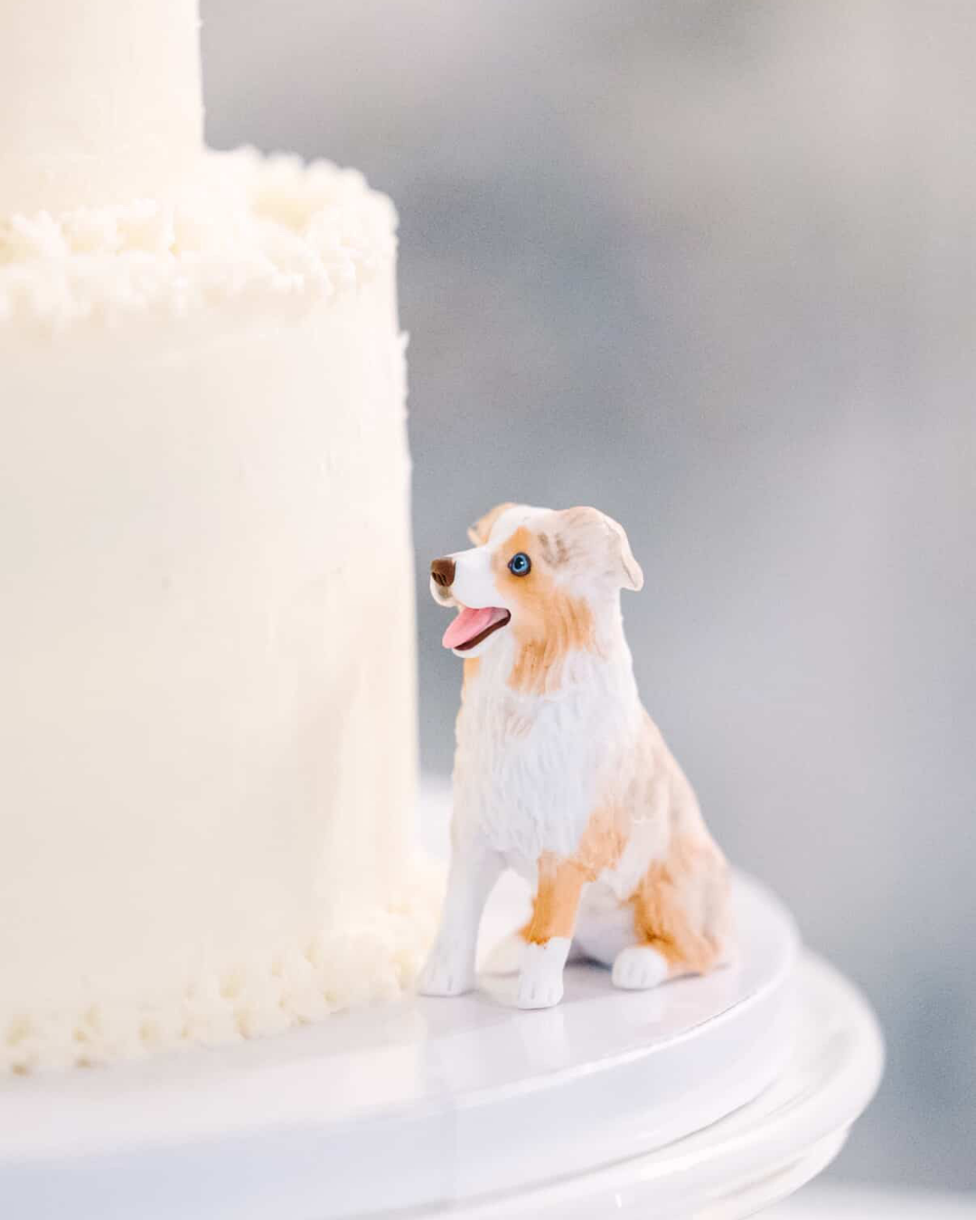 white two tiered cake with white and brown dog figurine on the side