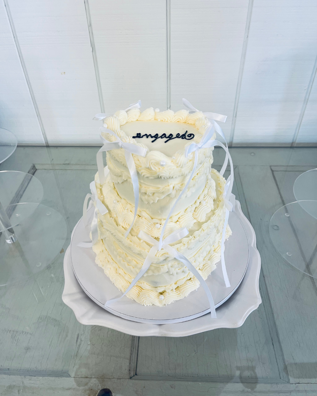 two tiered white heart engagement cake with bow details