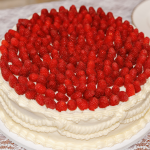 white cake with piping details with raspberries covering the top