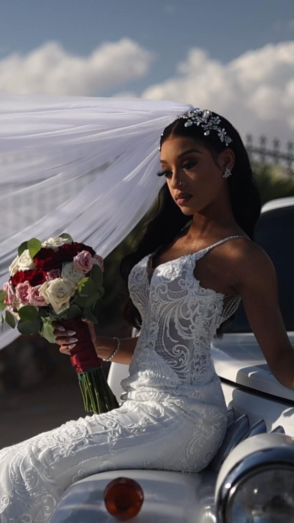 Bride in embellished lace gown with dramatic cathedral veil holding rose bouquet outdoors in El Paso