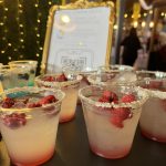 Raspberry cocktails with gold-rimmed glasses and fresh berries displayed at elegant event with string lights
