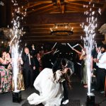 Newlyweds dip and kiss between sparkler fountains during rustic barn reception