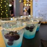 Blue ombré cocktails with gold sugar-rimmed glasses and fresh berries at festive party bar setup