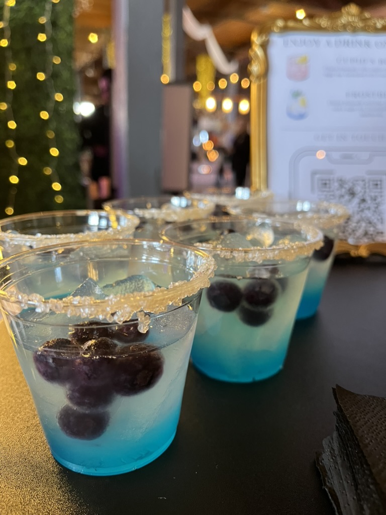 Blue ombré cocktails with gold sugar-rimmed glasses and fresh berries at festive party bar setup