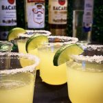 Classic margaritas with salt rims and lime garnish displayed with Bacardi and Smirnoff bottles