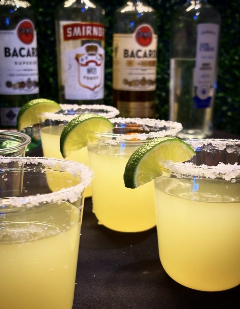 Classic margaritas with salt rims and lime garnish displayed with Bacardi and Smirnoff bottles