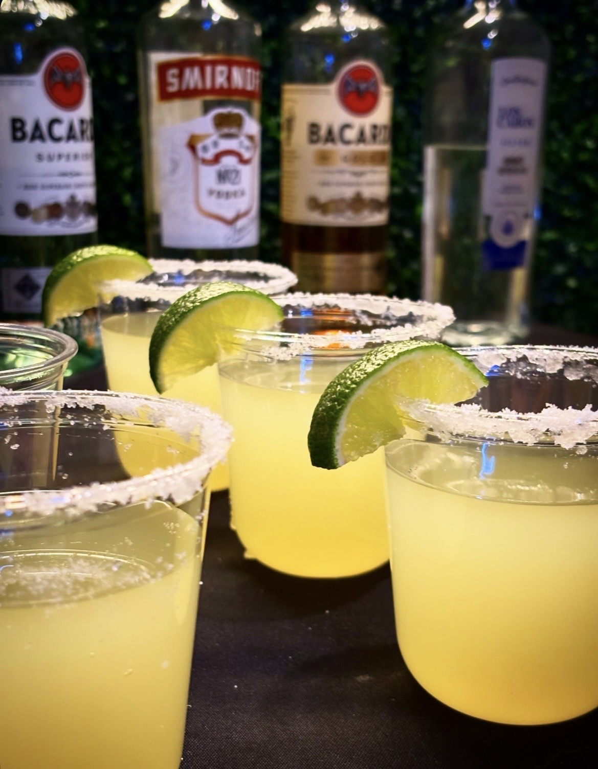 Classic margaritas with salt rims and lime garnish displayed with Bacardi and Smirnoff bottles