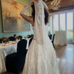 Bride in beaded wedding gown at Sunset Parlor reception hall with exposed brick, chandeliers, and elegantly set tables