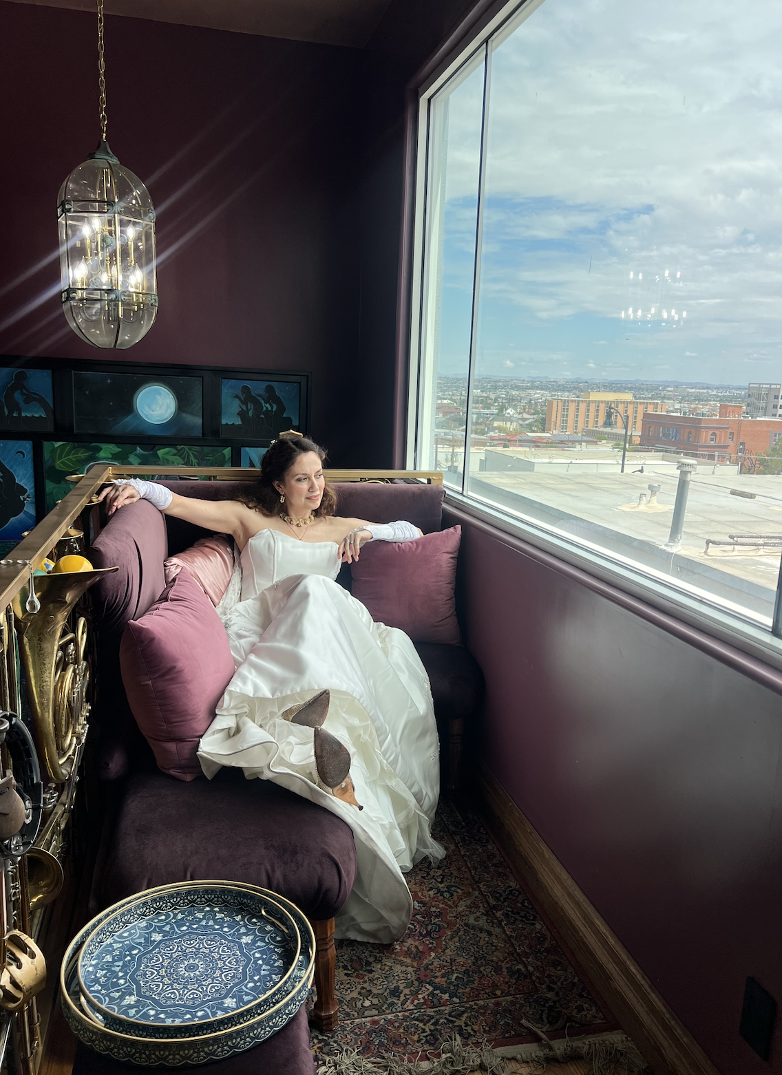 Bride relaxing on burgundy leather seating near large windows overlooking mountain views