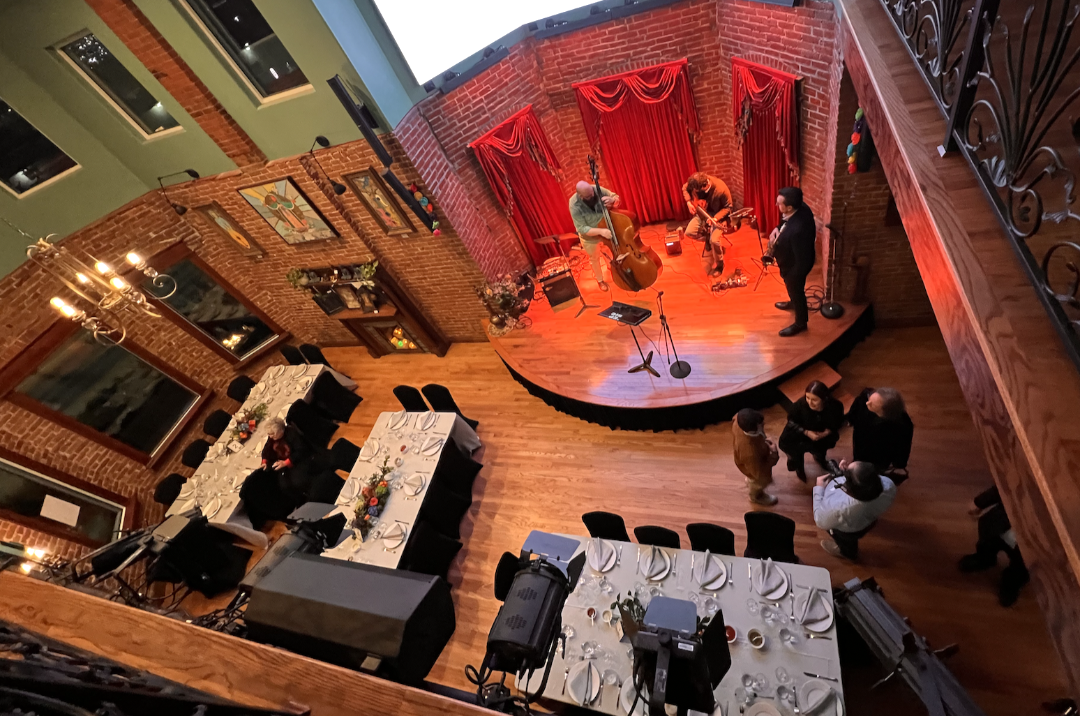 Aerial view of wedding reception with live band performing on stage surrounded by exposed brick walls and dining tables