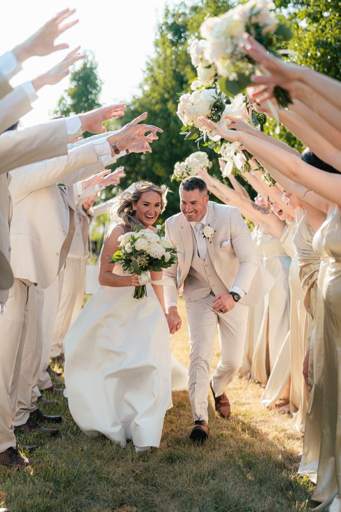 Bridesmaids in champagne dresses holding pink and white floral bouquets at outdoor wedding ceremony