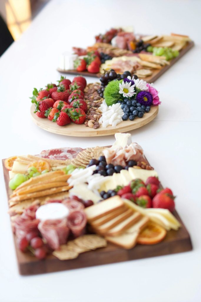 Artfully arranged charcuterie boards with fresh berries, cheeses, meats, crackers, and edible flowers