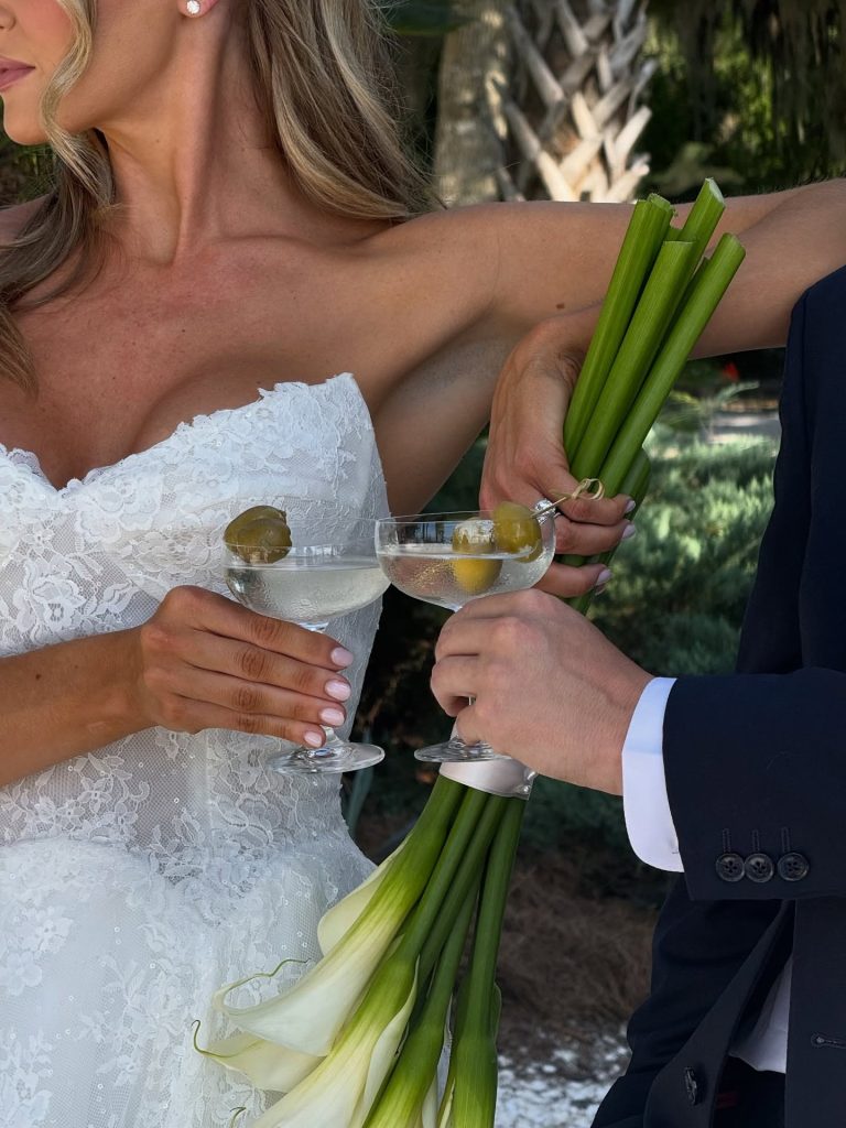 Bride and groom toasting with martinis while holding white calla lily bouquet at Savannah wedding