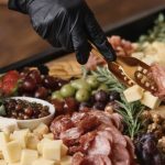 Fruit and Cheese Board with hand picking up cheese cube