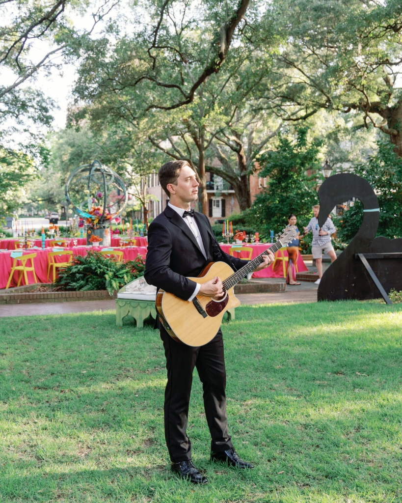 Formal wedding guitarist performing under oak trees at Savannah outdoor reception venue