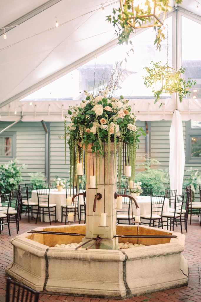 Wooden ceremony arch adorned with blush and ivory floral arrangement in bright venue space