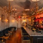 Elegant Nashville venue interior with gold chandeliers, marble bar, and warm amber lighting