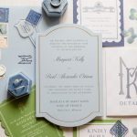 Elegant wedding invitation with gray border and calligraphy, surrounded by ribbon and blue flowers