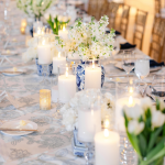 Wedding reception table with blue and white chinoiserie vases, white florals, and glowing candles