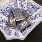 Personalized matchbooks with gold monograms displayed on blue-and-white chinoiserie plate