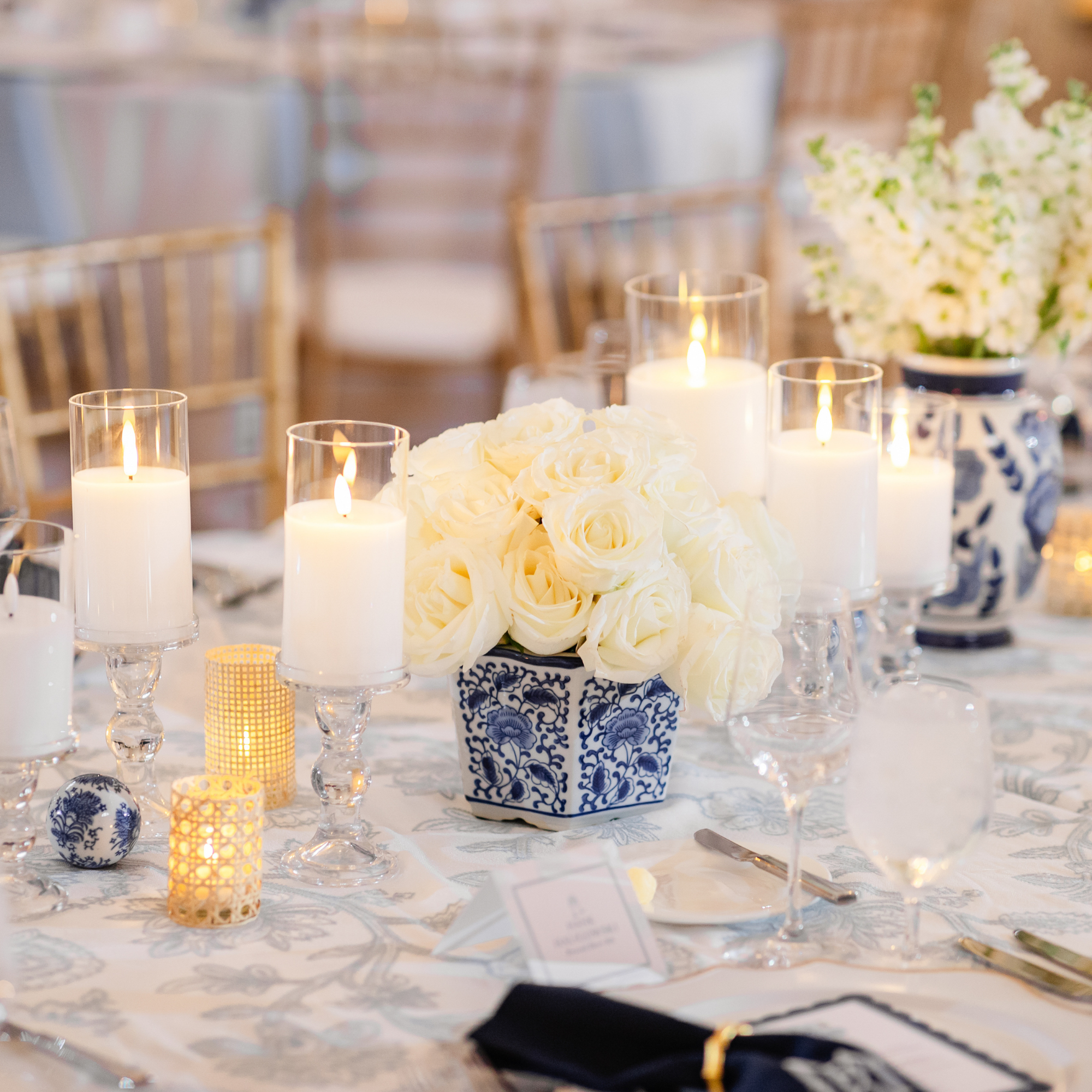 Close-up of wedding table centerpiece featuring white flowers in blue-and-white porcelain with candlelight