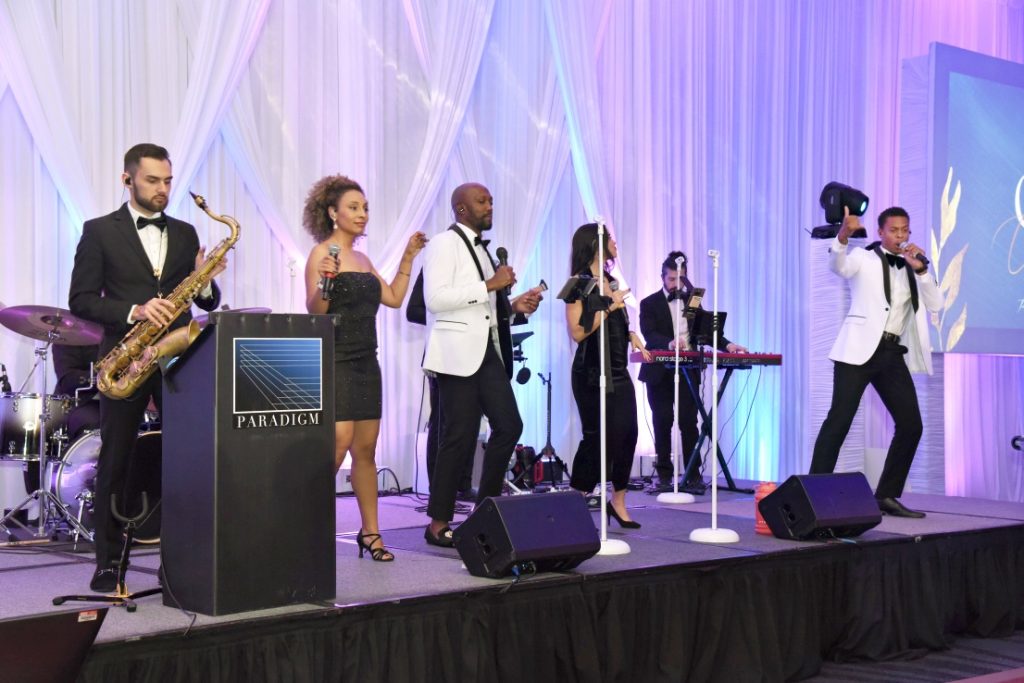 Paradigm Sounds live band performing at wedding reception with purple uplighting and white draping